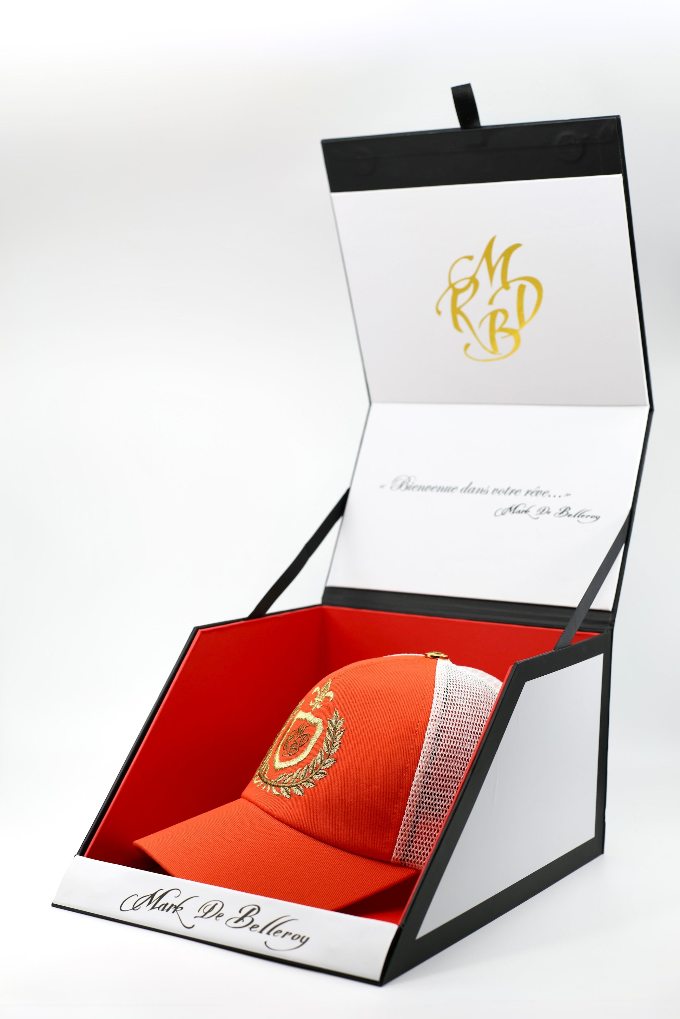 Casquette trucker de luxe orange et blanche l'orange majesté par Mark De Belleroy dans son écrin à casquette signature 