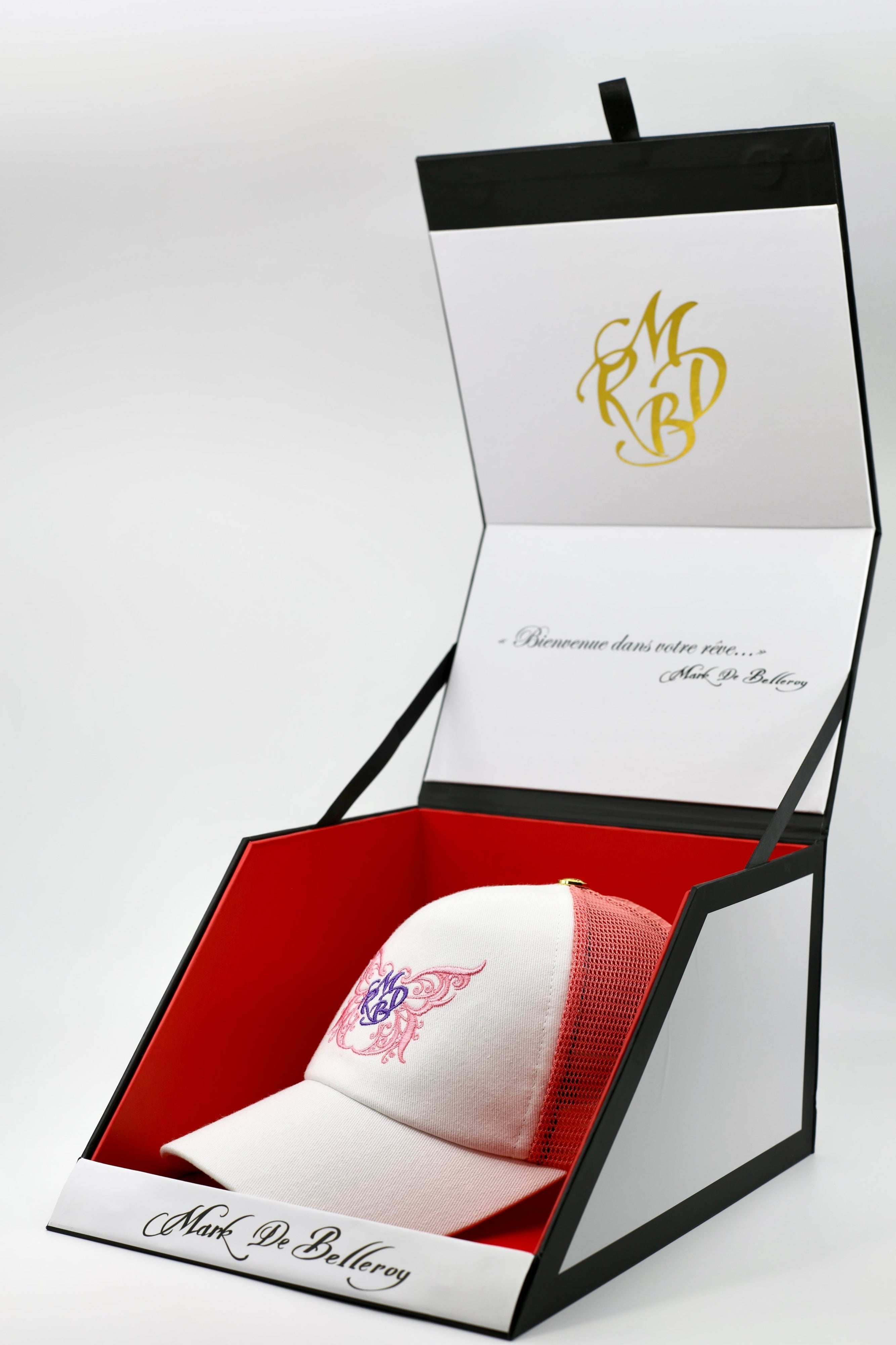 Casquette trucker de luxe rose et blanche le papillon précieux par Mark De Belleroy dans son écrin à casquette signature 